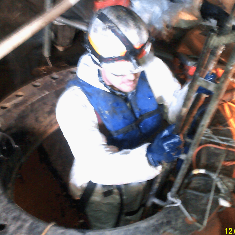 Worker in manway for discharge pipe repair.